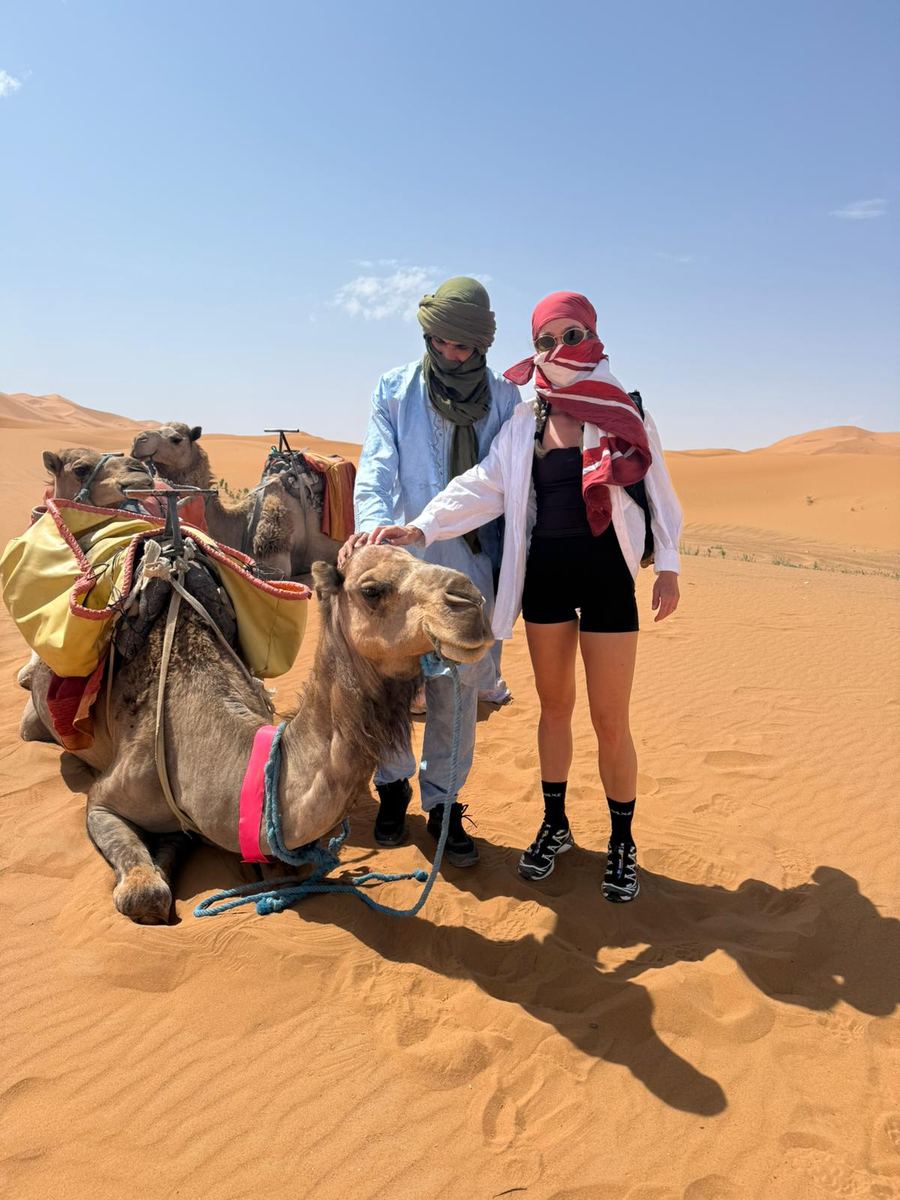 Berber camel guide in traditional blue robe standing in the dunes of Erg Chebbi