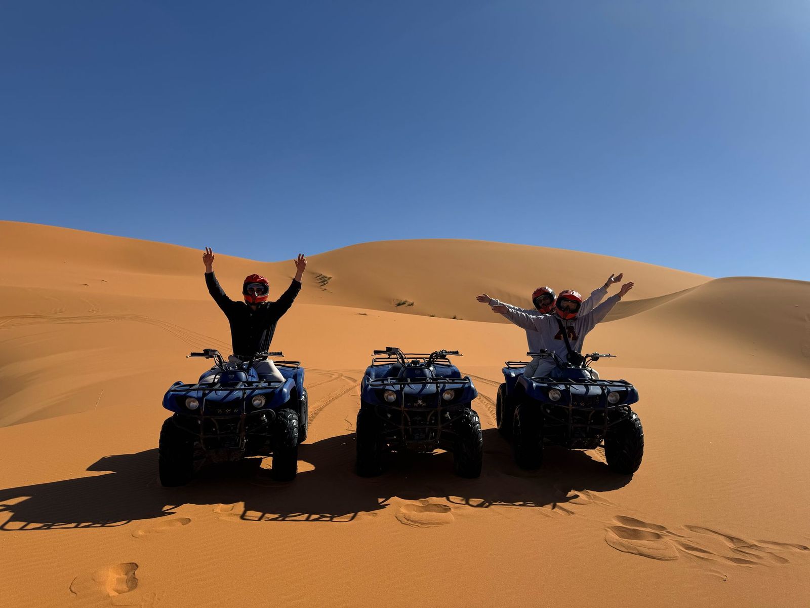 Travelers riding quad bikes across the dunes of Erg Chebbi near Merzouga, Morocco
