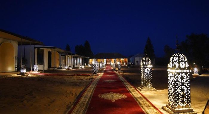 Lantern-lined pathway leading into the Morocco Desert Nights camp at blue hour