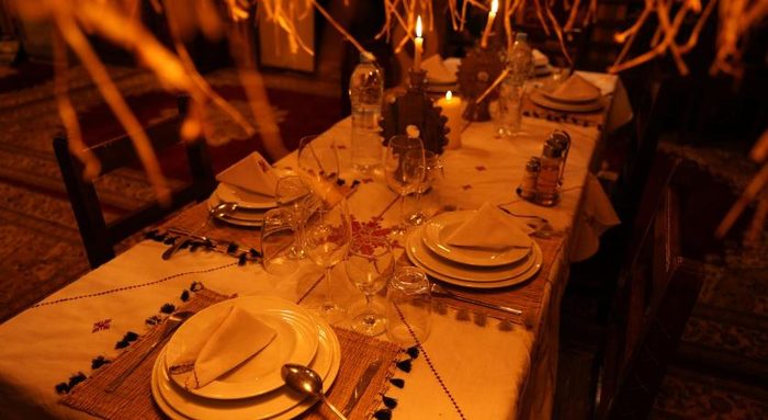 Candlelit dinner table set for guests at a Morocco Desert Nights camp